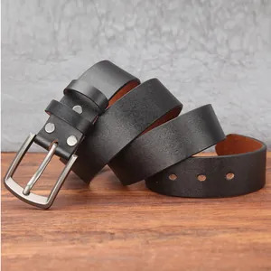 Detail of matte black genuine leather belt with brushed silver pin buckle on wood