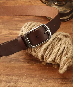 Dettaglio cintura in pelle marrone scuro con fibbia argento vintage su legno