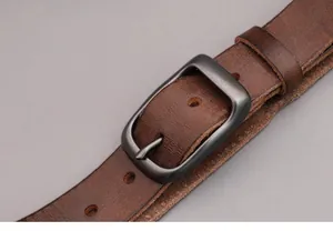 Macro shot of retro dark brown cowhide leather belt texture with antique metal buckle