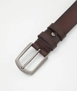 Detail of dark brown leather belt with matte silver buckle and fine stitching