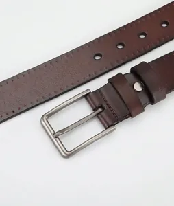 Detail eines dunkelbraunen Ledergürtels mit Metall-Dornschließe und präzisen Nähten