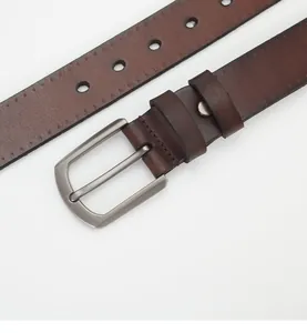Macro shot of dark brown genuine leather belt with a vintage matte metal pin buckle