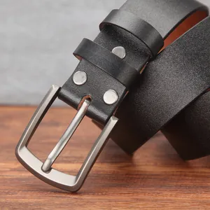 Men's premium black cowhide leather belt with a brushed metal pin buckle on wood