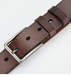 Detail of dark brown leather belt with matte metal pin buckle and stitching