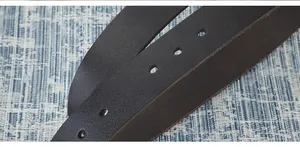 Macro de la ceinture en cuir marron foncé montrant les trous et les détails de couture