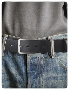 Gros plan d'une ceinture en cuir noir avec boucle argentée brossée sur un jean