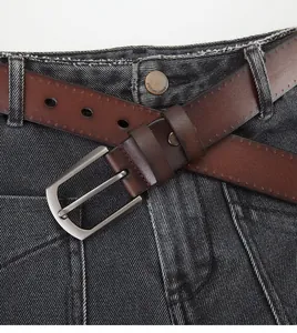 Close-up of brown genuine leather belt with matte silver pin buckle on jeans
