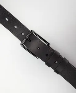 Detail of genuine cowhide leather belt with gunmetal alloy buckle and natural grain texture