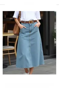 Détail d'une jupe midi en jean bleu clair avec coutures décoratives et ceinture en cuir marron