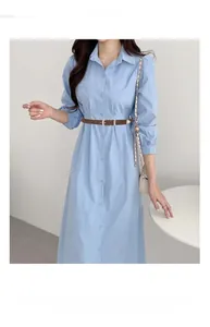 Slim dark brown leather belt with silver buckle worn on a blue dress for styling