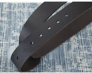 Détail macro d'une ceinture en cuir naturel montrant les trous et la texture fine
