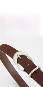 Detail of dark brown matte suede leather belt with polished silver oval buckle