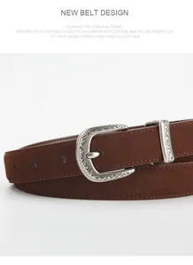 Close-up of a vintage dark brown suede belt with an intricately engraved silver horseshoe buckle