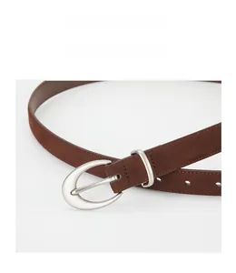 Close-up of matte dark brown suede belt with silver oval buckle and precise stitching