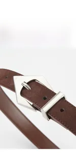 Close-up of dark brown suede leather belt with silver geometric metal buckle detail