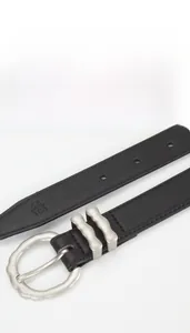 Détail d'une ceinture en cuir de vachette avec boucle argentée mate et marquage