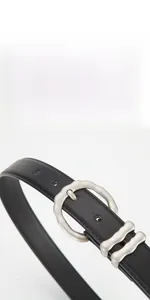 Détail de la ceinture en cuir noir pour femme avec boucle argentée mate à texture ondulée