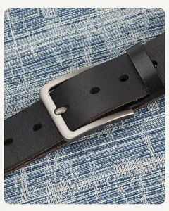 Détail macro d'une ceinture en cuir noir avec boucle en métal argenté brossé et tissu