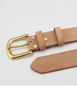 Dettaglio ravvicinato di una cintura in pelle vintage con fibbia in ottone opaco e rivetti