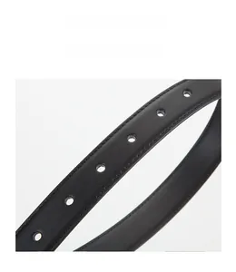 Détail macro de la ceinture en cuir noir avec surpiqûres précises et trous de réglage