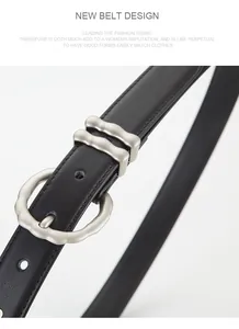 Détail d'une fine ceinture en cuir noir avec une boucle ondulée en métal argenté mat