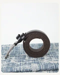 Détail de ceinture en cuir marron foncé avec boucle ardillon argentée et texture naturelle