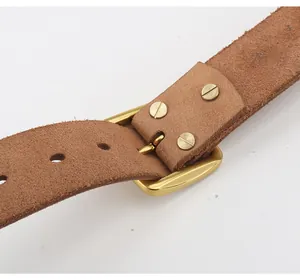 Dettaglio della cintura in pelle marrone con fibbia dorata e chiusura a vite vintage