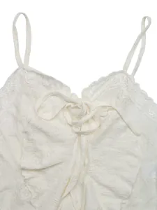 Close-up of white lace camisole with delicate floral patterns and a ribbon bow detail