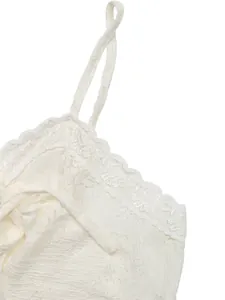 Detail of white lace camisole showing delicate crochet edges and wavy fabric texture