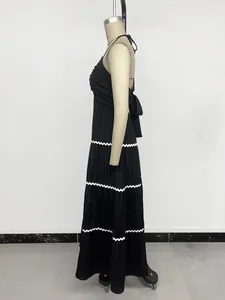 Detail of pleated black maxi dress with white wavy trim and elegant back bow tie