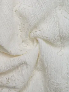 Close-up of white lace fabric featuring detailed floral hollow patterns and soft texture