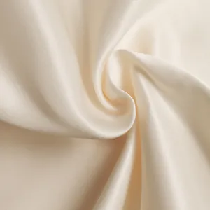 Detail shot of elegant cream satin fabric texture with smooth silk-like finish and drape