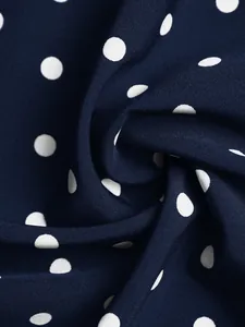 Close-up of navy blue fabric with white polka dots showing fine textile texture