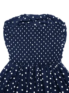 Detailed view of navy blue polka dot dress featuring elastic smocked chest and ruffled trim