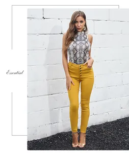 Detail of snake skin print halter top paired with yellow high-waisted button pants