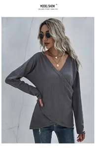 Detail of grey waffle knit long sleeve top featuring asymmetric V-neck and overlap hem