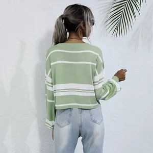 Back view of woman wearing a green and white striped long sleeve knit sweater with jeans