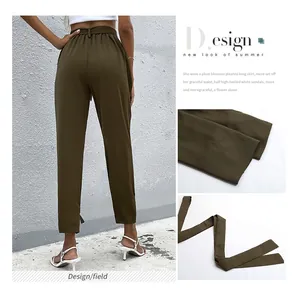 Dettaglio della vita alta con cintura e polsini affusolati sui pantaloni estivi verdi