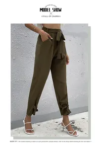 Dettaglio dei pantaloni verde oliva a vita alta con cintura a fiocco e lacci alle caviglie