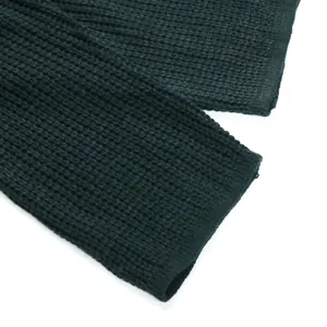 Detail shot of the dark green rib knit fabric texture and hem of the sweater dress