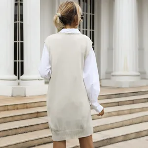 Back view of a beige cable knit vest dress layered over a white long sleeve shirt