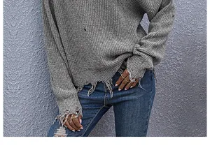 Detail showing distressed fringe and ripped texture on grey knit sweater hem and cuffs