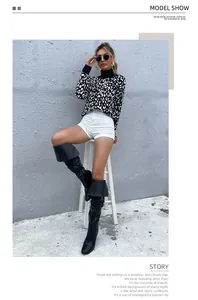 Gros plan sur un pull en maille léopard avec un short blanc et des bottes cuissardes noires