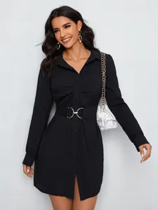 Detail of the waist belt with gold metal buckles on a black long sleeve shirt dress