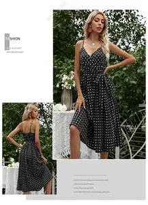 Polka dot summer dress with V-neck, spaghetti straps and waist tie in a garden setting