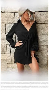 Détail d'une robe chemise noire à manches longues avec lien à la taille et boutons