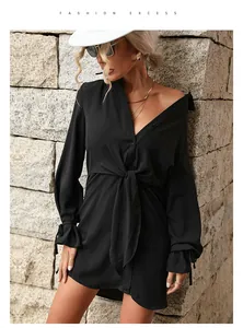 Détail d'une robe chemise noire à manches longues avec nœud à la taille et poignets volantés