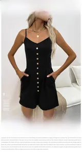Detailed shot of black romper showing the thin straps, wooden buttons, and waist pockets
