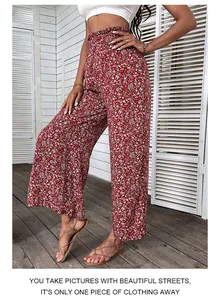 Detail view of high waist smocked elastic waistband on red floral wide leg trousers
