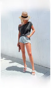 Outdoor model shot of women's grey off-shoulder top and frayed denim shorts outfit